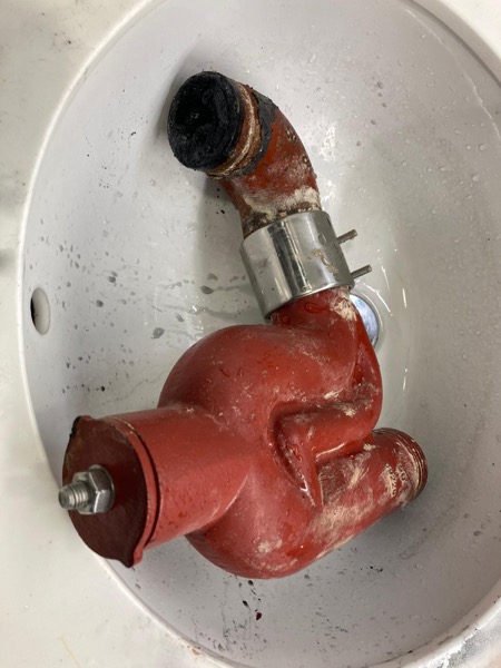DrainFix HK 從廚房水盆拆出嘅紅鑄鐵 P-trap 完整擺喺白瓷盆 — 透明診斷