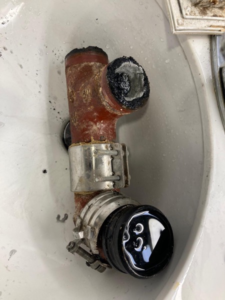 DrainFix HK 紅鑄鐵 T-fitting 完整拆解擺喺白瓷盤，stainless coupling + 黑色 rubber seal 分開排好